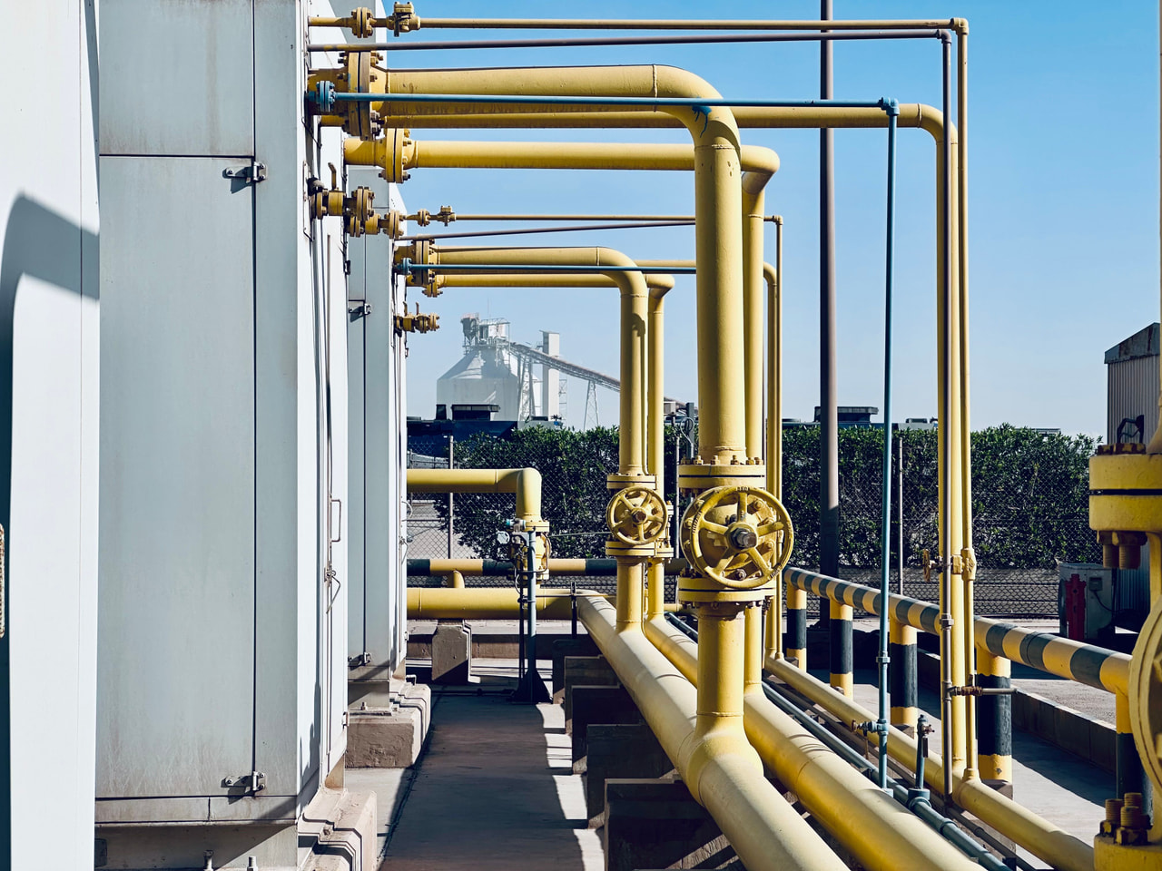 Yellow gas process piping and hand-wheel valves at an industrial plant